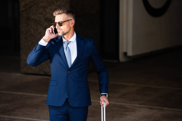 handsome businessman in suit and glasses talking on smartphone  - 写真・画像
