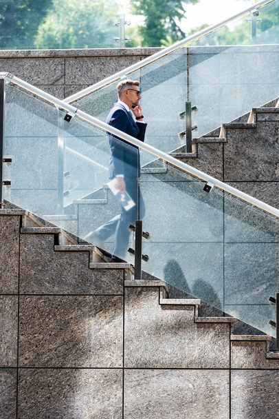 handsome businessman in suit and glasses talking on smartphone  - Foto, Bild