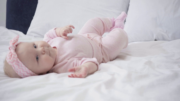 Selektiver Fokus des glücklichen Säuglings, der sich auf dem Bett überschlägt  - Filmmaterial, Video