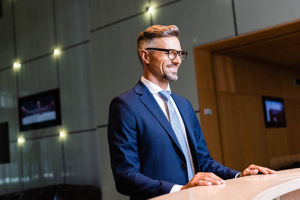 handsome businessman in suit and glasses smiling and looking away  - Foto, Bild