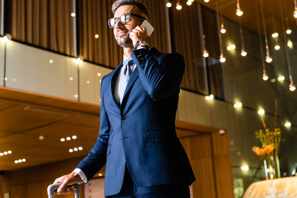 handsome businessman in suit and glasses talking on smartphone  - Foto, imagen