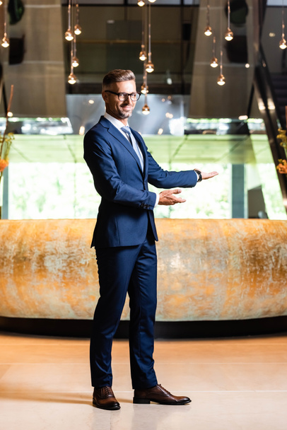 όμορφος επιχειρηματίας με κοστούμι και γυαλιά που δείχνουν με τα χέρια - Φωτογραφία, εικόνα