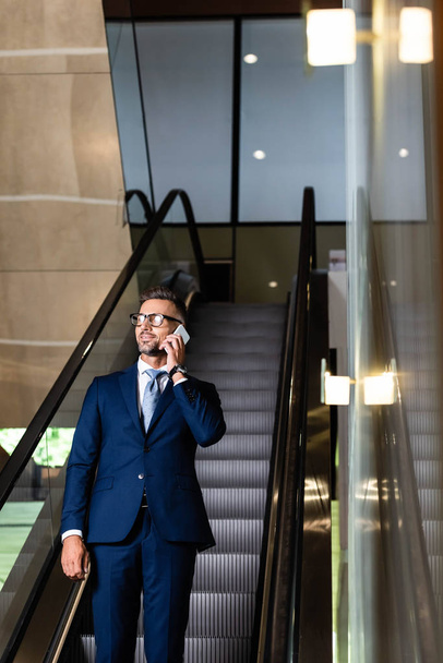 handsome businessman in suit and glasses talking on smartphone  - Photo, Image