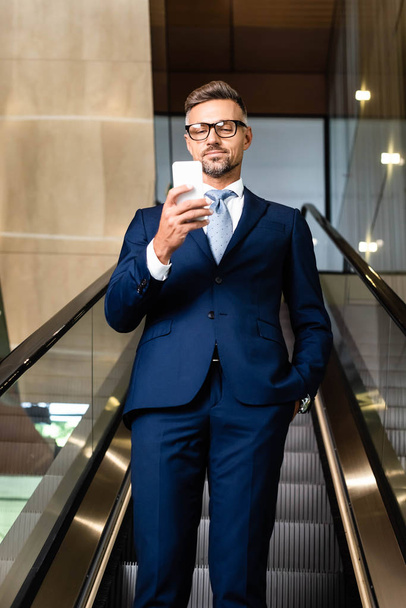 handsome businessman in suit and glasses talking on smartphone  - Fotó, kép