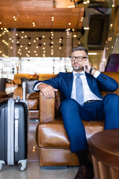 handsome businessman in suit and glasses talking on smartphone  - Fotó, kép