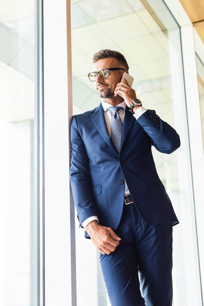 handsome businessman in suit and glasses talking on smartphone  - Valokuva, kuva