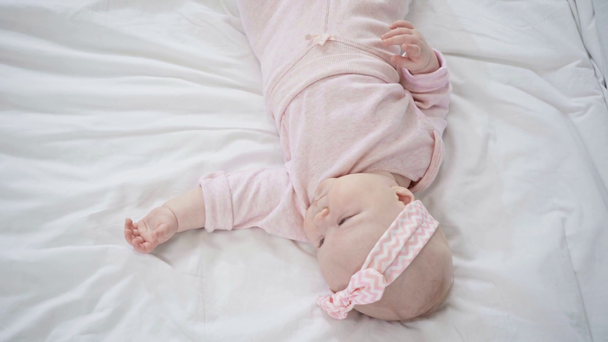 Κορυφαία θέα του αξιολάτρευτο μωρό που βρίσκεται στο κρεβάτι  - Πλάνα, βίντεο