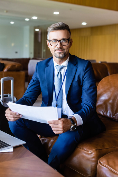 handsome businessman in formal wear and glasses holding documents  - Foto, Imagen