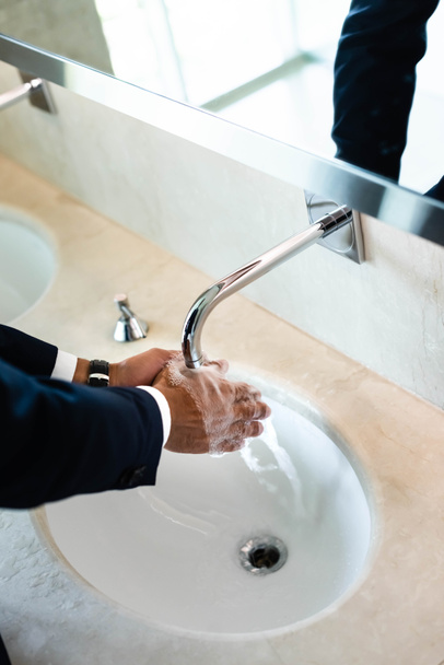 vista de ángulo alto del hombre lavándose las manos en el baño público
  - Foto, Imagen
