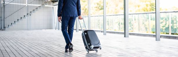 panoramic shot of businessman in formal wear holding suitcase  - Foto, Bild