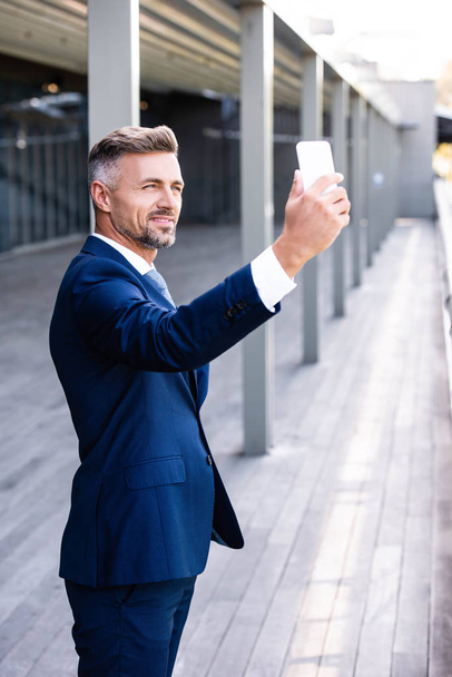 przystojny i pewny siebie biznesmen w formalnym nosić mówić selfie  - Zdjęcie, obraz