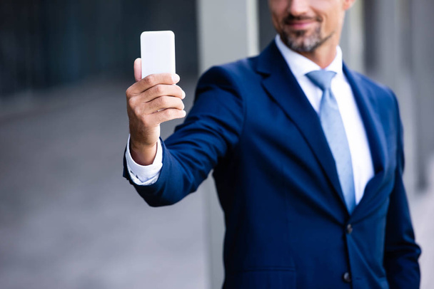 cropped view of businessman in formal wear talking selfie  - Fotó, kép