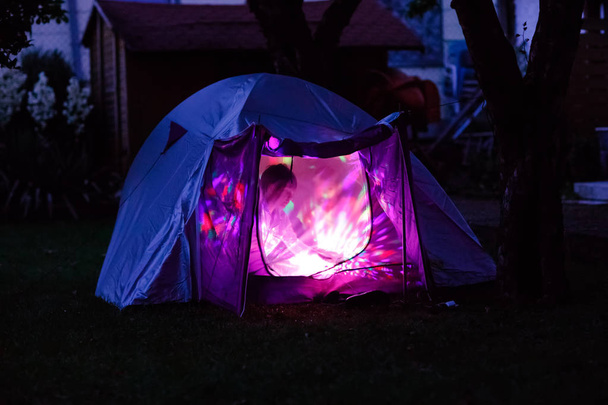 Zelt mit Kindern drinnen leuchtet in der Nacht. Kinder, die im heimischen Garten übernachten. Abenteuer in den Sommerferien - Foto, Bild