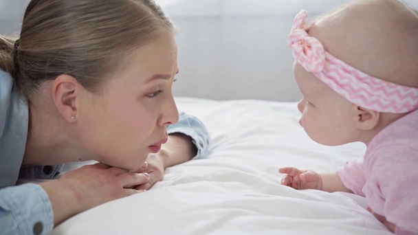 ευτυχισμένη μητέρα παίζοντας με το βρέφος κόρη στο κρεβάτι  - Πλάνα, βίντεο