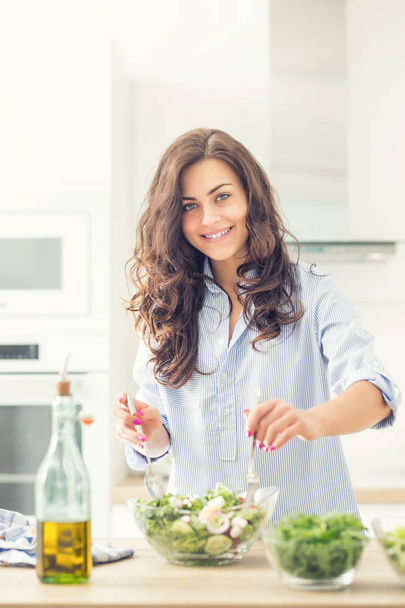 Young woman preparing vegetable salad in her kitchen. Healthy li - Valokuva, kuva