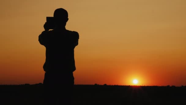 Silueta muže, který fotografuje západ slunce - Záběry, video