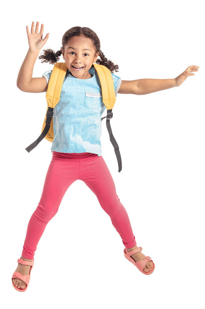 Jumping little African-American schoolgirl on white background - Foto, afbeelding