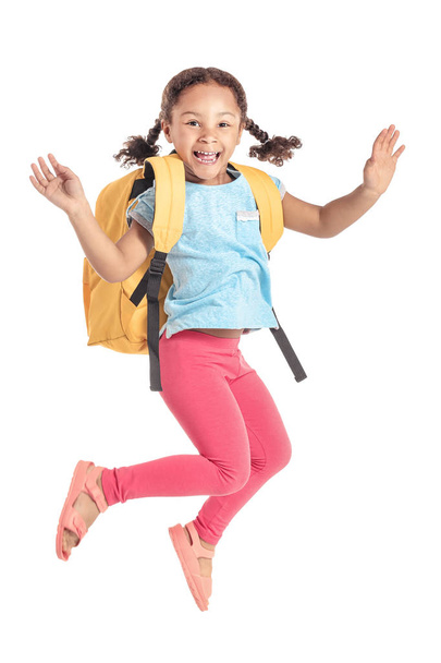 Jumping little African-American schoolgirl on white background - Foto, afbeelding