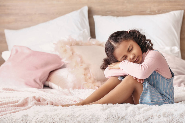 traurige kleine afrikanisch-amerikanische Mädchen sitzt auf dem Bett - Foto, Bild