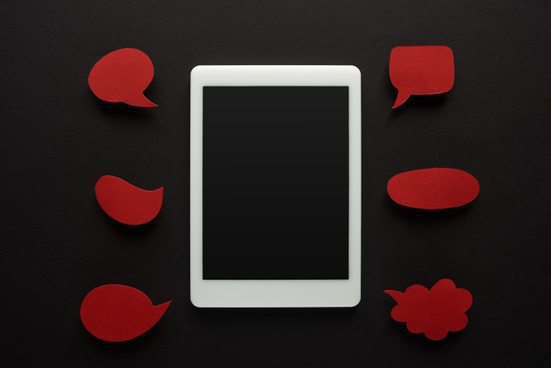 a digitális tabletta felső nézete üres képernyő fekete háttérrel, üres piros szövegbuborékokkal, online zaklatás - Fotó, kép