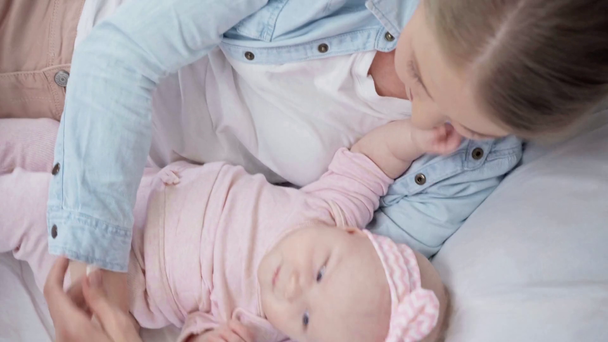 Κορυφαία θέα της ευτυχης μητέρας που κείτεται στο κρεβάτι με το μωρό  - Πλάνα, βίντεο