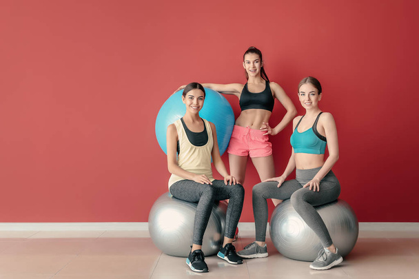 Young sporty women with fitballs near color wall - Foto, Bild