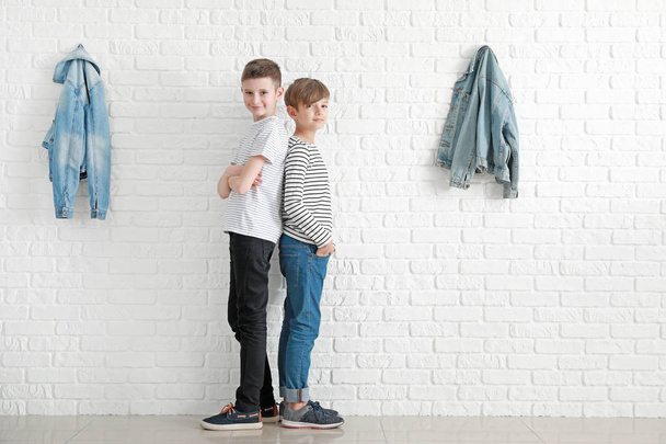 Chicos con estilo en jeans cerca de la pared de ladrillo blanco
 - Foto, imagen