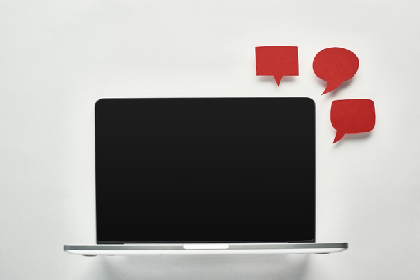 laptop-val üres képernyő-ra fehér háttér mellett üres piros beszéd buborék, cyberbullying fogalom - Fotó, kép