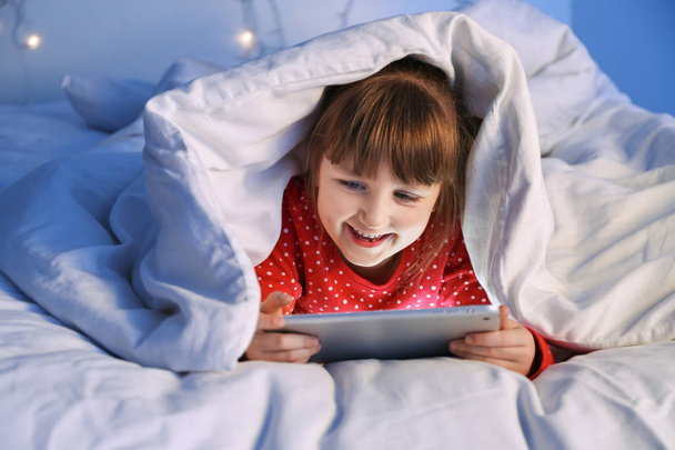 Cute Little Girl przy użyciu komputera typu Tablet w łóżku w nocy - Zdjęcie, obraz