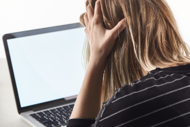 offended blonde girl as victim of cyberbullying sitting near laptop with blank screen - Photo, Image