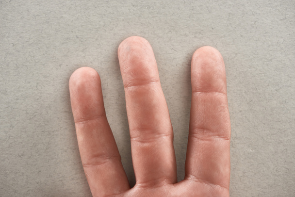 vista parcial del hombre mostrando tres dedos sobre fondo gris
 - Foto, Imagen