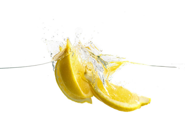 Falling of cut lemon into water on white background - Photo, image