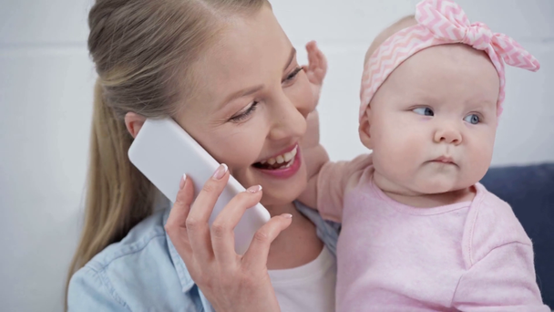 bebé tocando la cara de la madre hablando en el teléfono inteligente
  - Metraje, vídeo