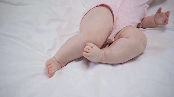 περικομμένη όψη του μωρού που κυλάει στο κρεβάτι  - Πλάνα, βίντεο