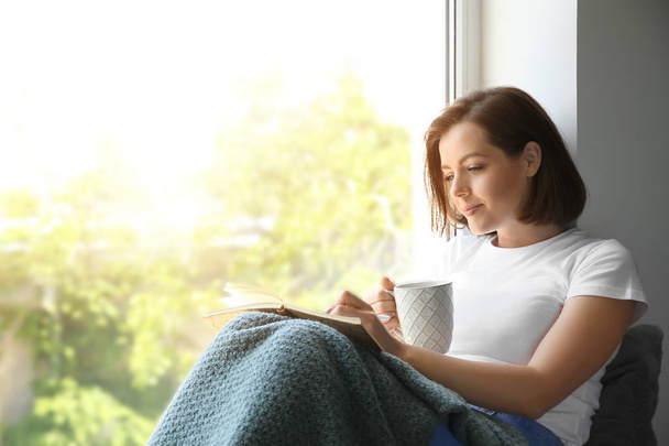 Rano pięknej młodej kobiety picie kawy podczas pisania w Notatniku w pobliżu okna - Zdjęcie, obraz