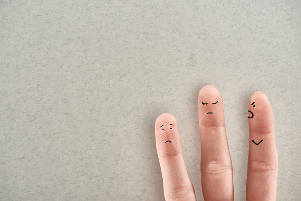 частичный взгляд человека, показывающего три пальца, символизирующие агрессивного насильника и грустных жертв на сером фоне
 - Фото, изображение