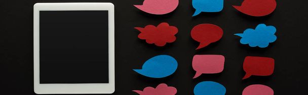 panoramic shot of digital tablet with blank screen on black background near empty speech bubbles, cyberbullying concept - Photo, Image
