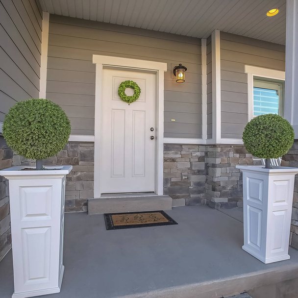 ドアに花輪と木と石のレンガの壁の組み合わせを持つ正方形の家 - 写真・画像