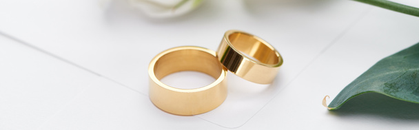 panoramic shot of golden wedding rings on white envelope  - Photo, image