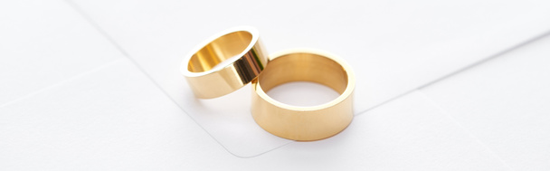 panoramic shot of golden rings on white envelope - Zdjęcie, obraz