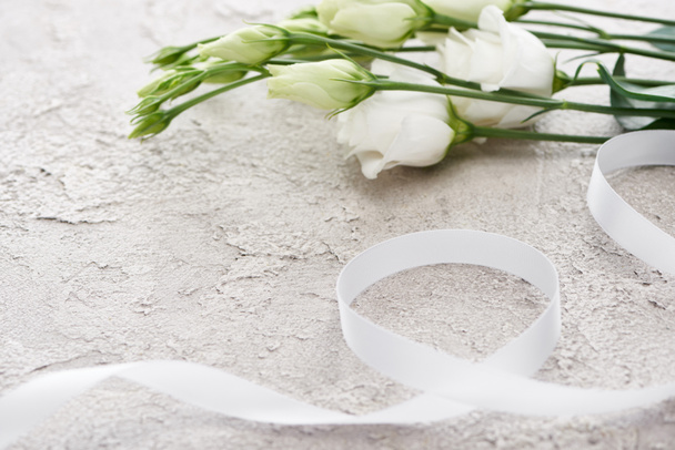  bílé eustomské květy v blízkosti stužky na texturované ploše, svatební koncepce   - Fotografie, Obrázek