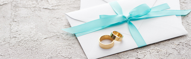 tiro panorâmico de anéis dourados no envelope branco com fita azul
 - Foto, Imagem