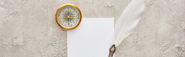 panoramatický záběr brzného pera na bílé kartě v blízkosti Zlatého kompasu na šedé texturované ploše - Fotografie, Obrázek