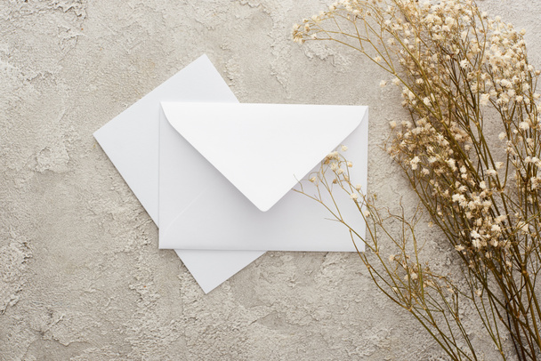 top view of piece of white envelope and card near flowers on textured surface - 写真・画像