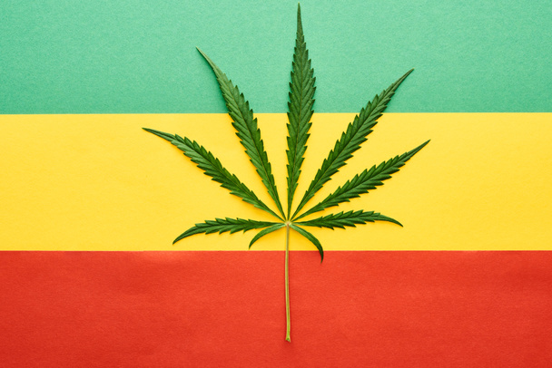 Ansicht des Cannabis-Blattes auf dem Hintergrund der rastafarischen Flagge - Foto, Bild