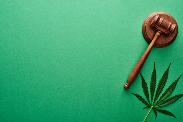 top view of green cannabis leaf near wooden gavel on green background with copy space - Photo, Image