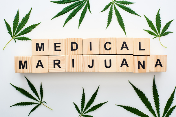 pohled na konopná listí a dřevěné bloky s lékařskými slovy marihuany na bílém pozadí - Fotografie, Obrázek
