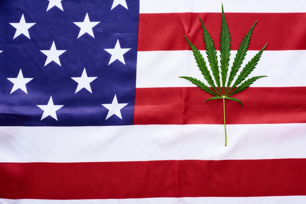 Κορυφαία όψη του πράσινου φύλλου κάνναβης στο φόντο της αμερικανικής σημαίας - Φωτογραφία, εικόνα