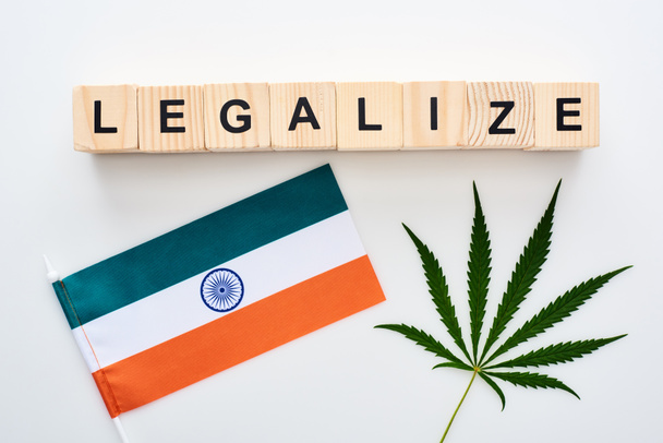 top view of green cannabis leaf and legalize lettering on wooden cubes near flag of India on white background - Foto, Imagem