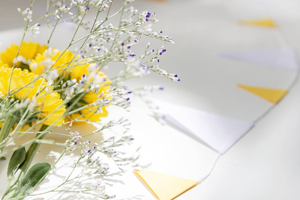 黄色い菊の花束は、旗の花輪に囲まれた白いテーブルの上にあります. - 写真・画像